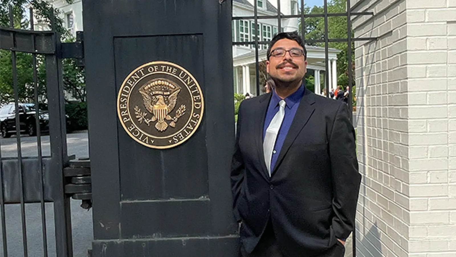 Caleb González smiles next to a pillar bearing the seal of the vice-president of the United States